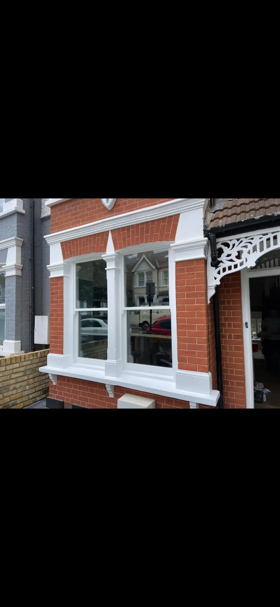 Restored Victorian timber sash windows with authentic horns and white masonry surrounds on a red-brick period terrace