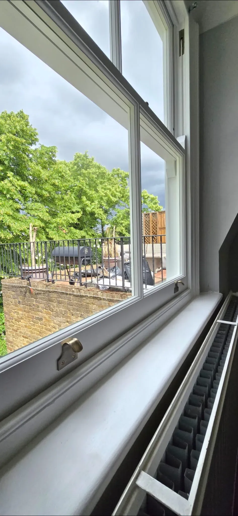 Restored white timber sash window with brass sash lifts and slimline double glazing in a period home